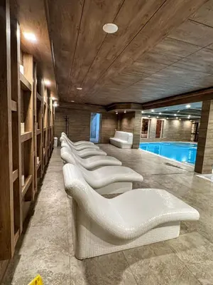 a row of white chairs in a room with a pool at Bóris House in Ognyanovo