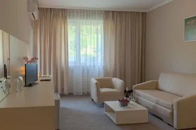 a living room with a couch and a tv at Парк хотел Кюстендил in Kyustendil