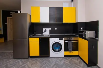 a kitchen with a washing machine and yellow cabinets at The yellow appartment in Sofia