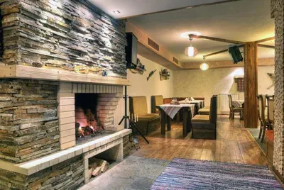 a living room with a stone fireplace with a table at Форест Нук - апартамент in Pamporovo