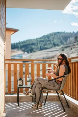 a woman sitting in a chair on a balcony with a book at Katerina Apartments 2 in Velingrad