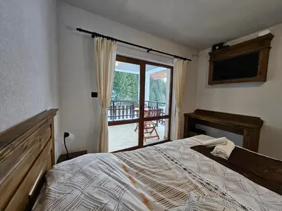 a bedroom with a bed and a view of a balcony at самостоятелна къща Планински перли, дом 1 на 5 мин от ски лифт Стойките, Пампорово in Stoykite