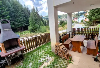 a porch with a fireplace and a picnic table and a stove at самостоятелна къща Планински перли, дом 1 на 5 мин от ски лифт Стойките, Пампорово in Stoykite