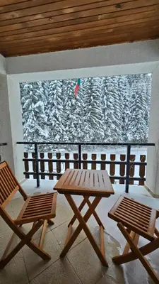 a picnic table and two chairs in front of a window at самостоятелна къща Планински перли, дом 1 на 5 мин от ски лифт Стойките, Пампорово in Stoykite