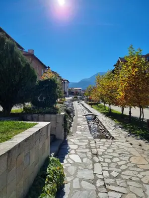 a stone path in a park with trees and a wall at Bansko Royal Towers apartment 200m from skilift in Bansko