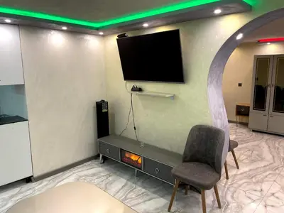 a room with a tv on a wall with a chair at Apartments Dream in Sarnitsa