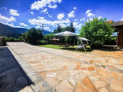 a stone patio with a table and an umbrella at Apartments Dream in Sarnitsa