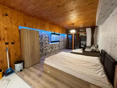 a bedroom with a bed and a stone wall at Apartments Dream in Sarnitsa