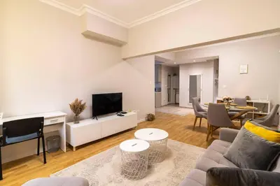 a living room with a couch and a television and a table at Spacious Aristocratic Apt. with a Colourful View in Sofia