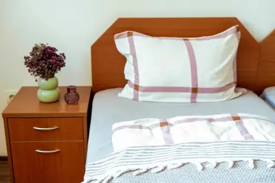 a bed with a pillow and a table with a vase of flowers at Large 2-bedroom apt near ski road, 5 min to Gondola & Bar Street in Bansko