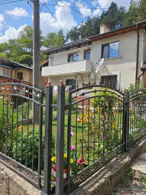a black iron fence with flowers in a yard at Апартамент за гости Криси гр. Девин in Devin