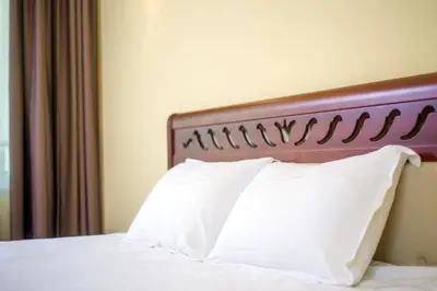 a bed with a wooden head board and white pillows at Парк-Хотел Клементина in Trud