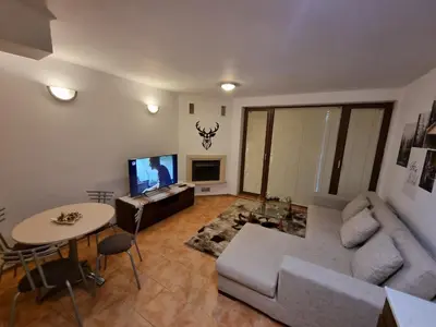 a living room with a couch and a table and a tv at Private Chalets Bansko in Bansko