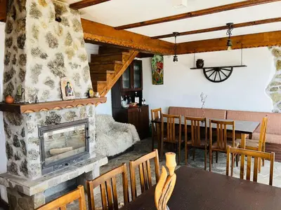 a living room with a fireplace and a dining room at Къща за гости Под Манастира in Skrino