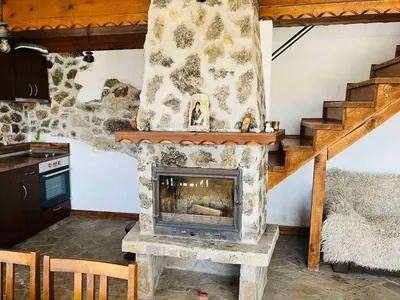 a living room with a fireplace and a staircase at Къща за гости Под Манастира in Skrino