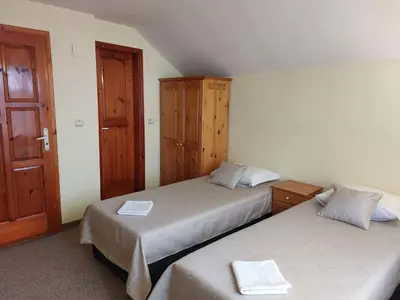 a bedroom with two beds and a wooden door at Стаи за гости Валеьови in Bansko