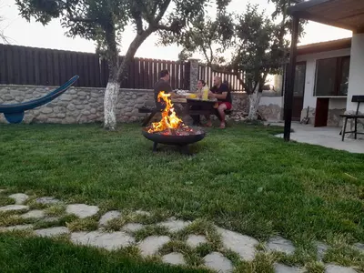 two people sitting around a fire pit in a yard at Ергини in Dobrinishte