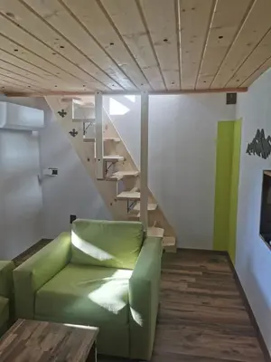 a living room with a green couch and stairs at Ергини in Dobrinishte