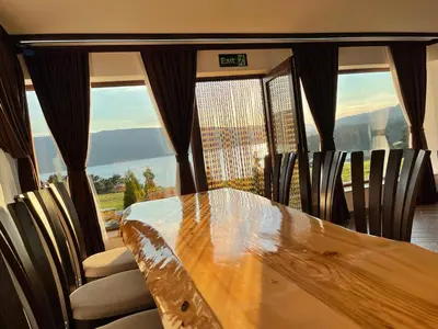 a dining room table with chairs and a large window at Villa ART in Dospat