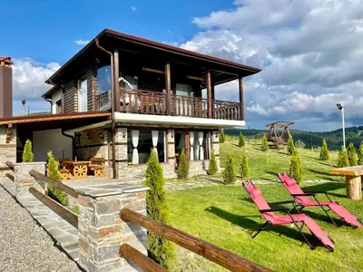 a house with a deck and two chairs in the yard at Villa ART in Dospat
