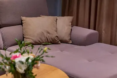 a couch with a pillow and a table with flowers at City Park Inn Apartment Verona in Plovdiv
