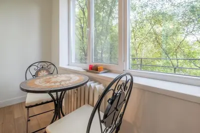 a table and two chairs in a room with windows at St. Ivan Rilski flat in Sofia