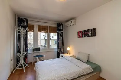 a bedroom with a bed and a desk and a window at Niko's 2 Bedroom Central Apartment in Sofia