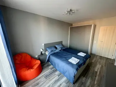 a bedroom with a blue bed and an orange chair at Habitat 29 Apartment in Sofia