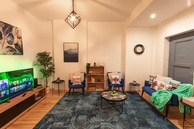 a living room with a flat screen tv and chairs at Vintage bohemian Paradise with Xbox Series X for BIG groups in Sofia