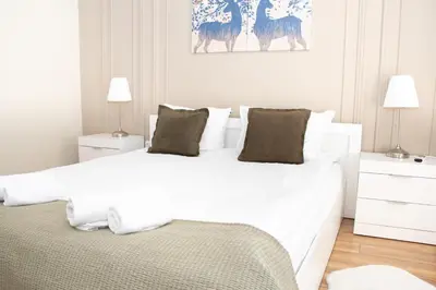 a white bedroom with two beds and two lamps at Gondola Apartments Lux in Bansko