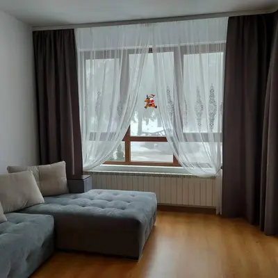 a living room with a couch and a large window at Семи гарден in Borovets