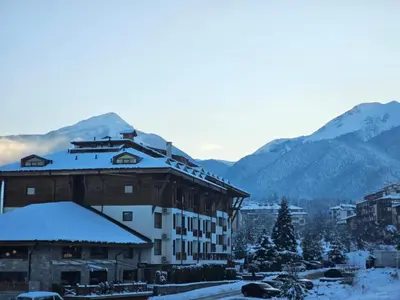 a building in the snow with mountains in the background at Apartment at Dream Bansko in Bansko