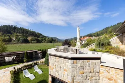 a house with a stone wall and a yard with a playground at Armaco Residence in Koprivshtitsa