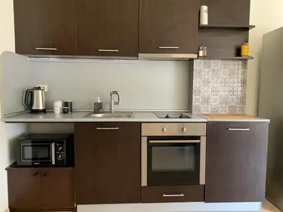 a kitchen with brown cabinets and a sink and a microwave at Central Art Apartment in Bansko with Mountain View in Bansko