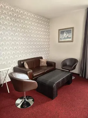 a living room with a leather couch and two chairs at Glamping Alliance Hotel in Plovdiv