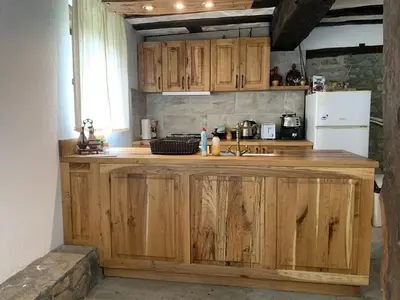 a kitchen with wooden cabinets and a white refrigerator at Къща за гости НОВЕ in Terziysko
