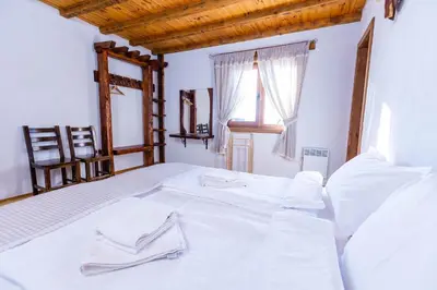 a bedroom with a bed with white sheets and a window at Комплекс Конна база Асгард in Golem Tsalim