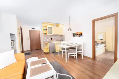a living room with a table and a kitchen at Snow Legend Apartment with terrace in Bansko