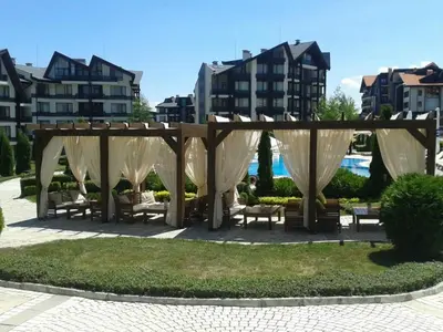 a gazebo with benches in a park with buildings at Aspen Golf Resort and SPA in Bansko
