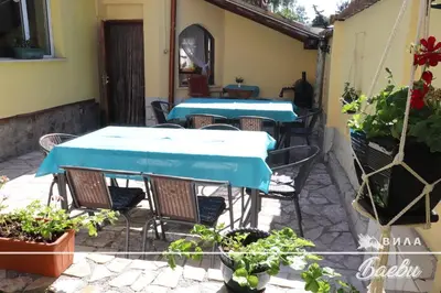 a patio with two tables and chairs and plants at ВИЛА БАЕВИ in Velingrad