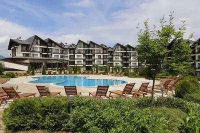 a resort with a pool and chairs and a building at Aspen studio Mountain retreat at Aspen Resort Golf Ski & Spa in Razlog
