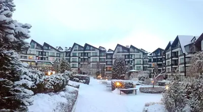 a courtyard covered in snow with apartment buildings at Aspen studio Mountain retreat at Aspen Resort Golf Ski & Spa in Razlog