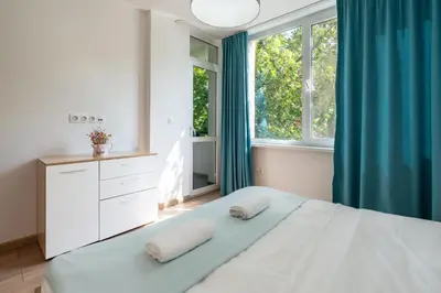 a bedroom with a bed with blue curtains and a window at Modern and Cozy 1BDR Apartment in the City Center in Sofia