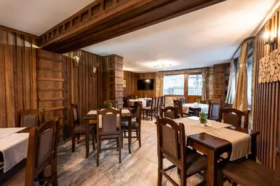 a restaurant with wooden walls and tables and chairs at Beluga Guest House in Velingrad