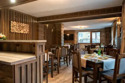 a restaurant with wooden walls and tables and chairs at Beluga Guest House in Velingrad