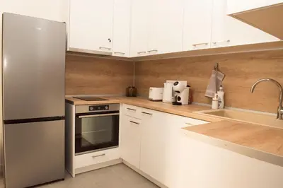 a kitchen with white cabinets and a stainless steel refrigerator at Top Center Designer Studio Apartment in Sofia