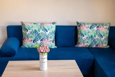 a blue couch with a vase with flowers on a table at Design Loft in the City Center in Sofia