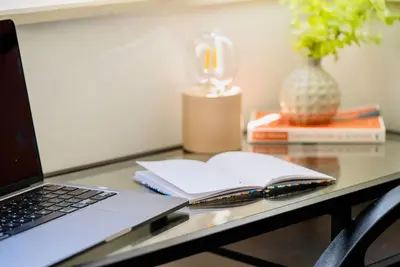 a laptop computer sitting on a desk with a book at Cozy 2-Bedroom Flat in the very Center of Sofia in Sofia
