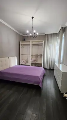 a bedroom with a purple bed and a chandelier at Doctors Garden Appartment in Sofia