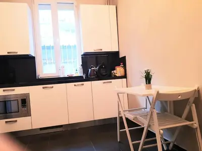 a kitchen with white cabinets and a table and a microwave at Doctors Garden Appartment in Sofia